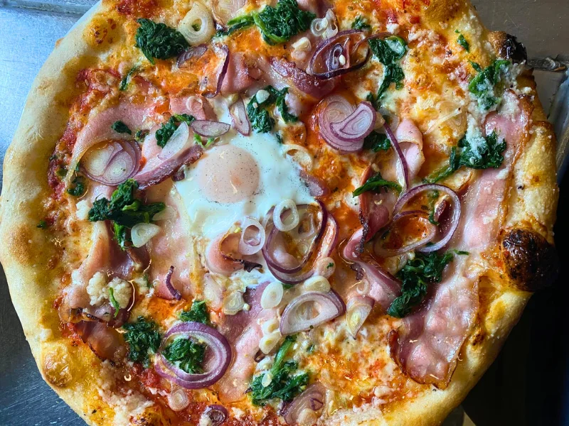 Pizza mit Schinken, Käse, Ei, Tomaten und Basilikum - hausgemacht im IBEX Nauders direkt an der B180