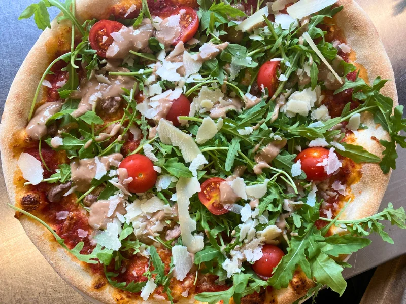 Steinofenpizza mit Rucola, Parmesan und frischen Tomaten - italienischer Genuss am Reschenpass in Nauders